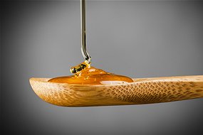 Honey dripping on wooden spoon