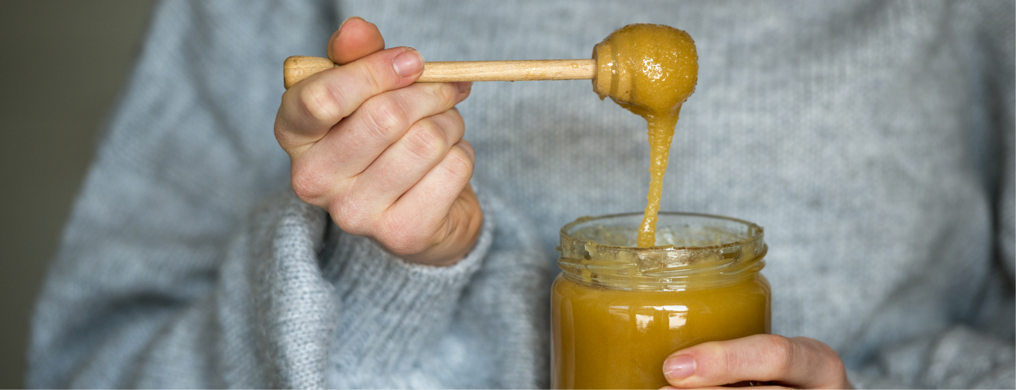 Woman scooping Manuka honey out of a jar